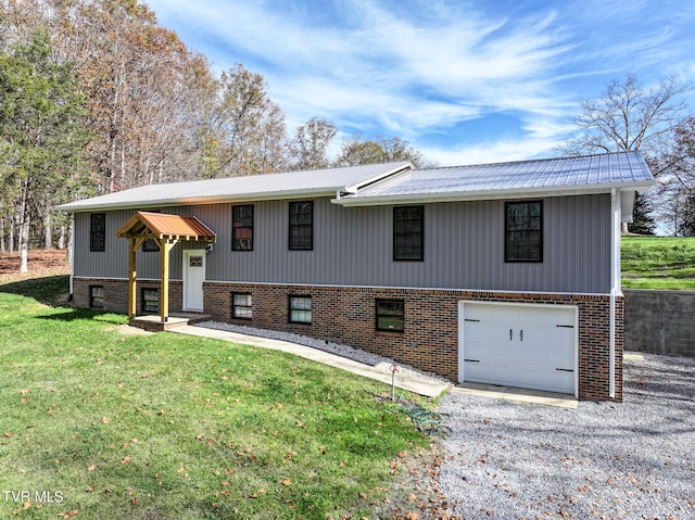 raised ranch with a front lawn, metal roof, driveway, and an attached garage