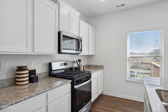 kitchen with light stone countertops, appliances with stainless steel finishes, dark hardwood / wood-style floors, and white cabinets