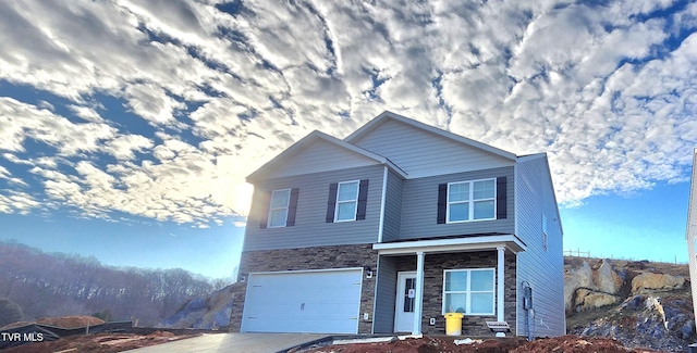 view of front of home with a garage, stone siding, and concrete driveway