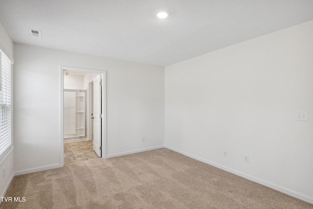 spare room with light colored carpet, visible vents, and baseboards