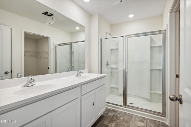 full bathroom with a stall shower, a walk in closet, and a sink