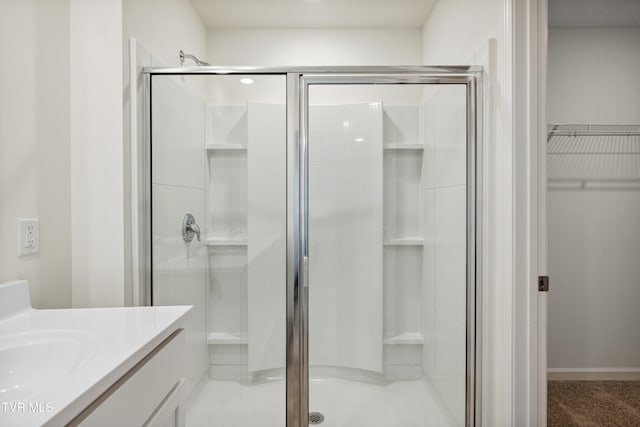 bathroom with a walk in closet, a shower stall, and vanity
