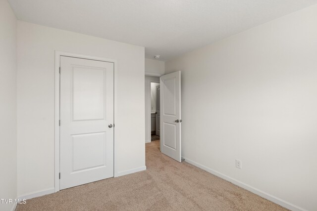 unfurnished bedroom with light carpet and baseboards