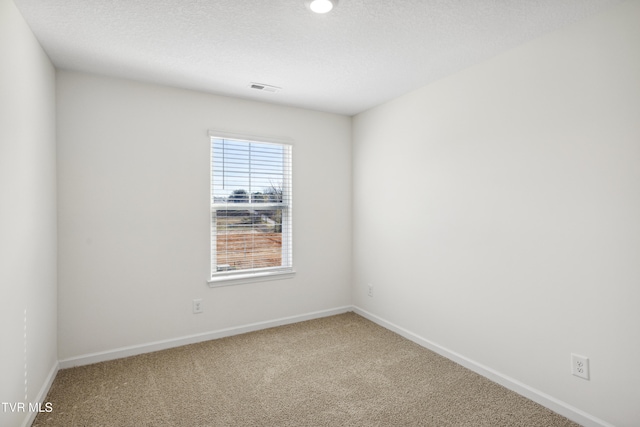 empty room with baseboards, carpet flooring, visible vents, and a textured ceiling