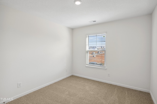 empty room featuring carpet floors, visible vents, a textured ceiling, and baseboards