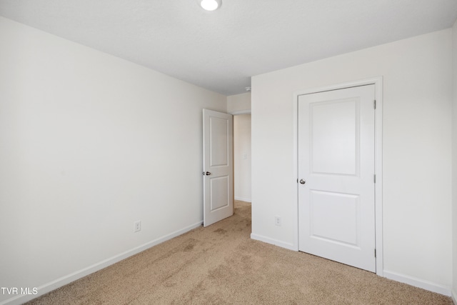 unfurnished bedroom featuring light carpet and baseboards