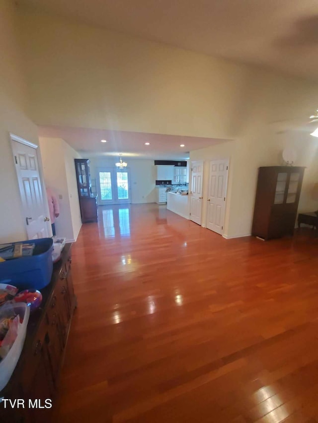 living room with a towering ceiling, a notable chandelier, hardwood / wood-style floors, and french doors