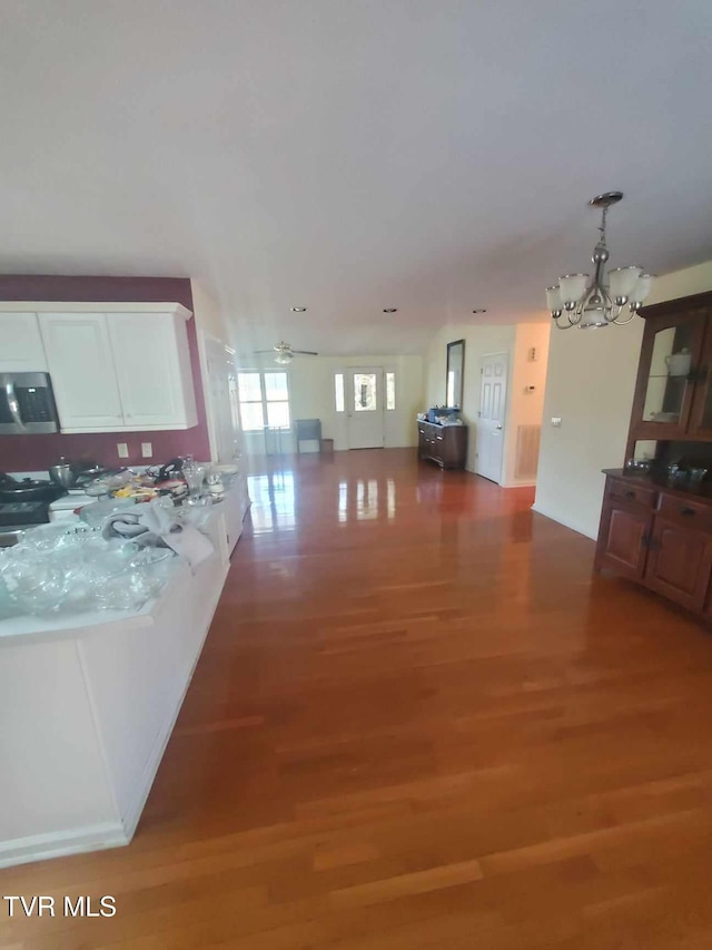 interior space with hardwood / wood-style flooring, pendant lighting, ceiling fan with notable chandelier, and white cabinets