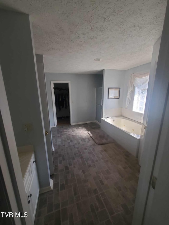 bathroom featuring vanity, a bathing tub, and a textured ceiling