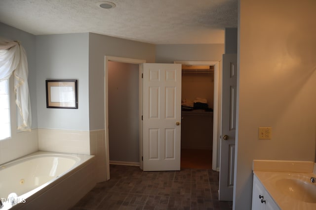 bathroom with vanity, a textured ceiling, and a bath