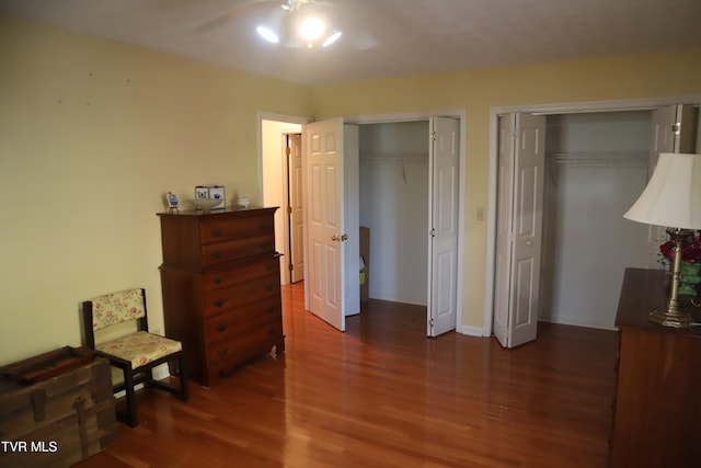 bedroom with dark hardwood / wood-style floors, multiple closets, and ceiling fan