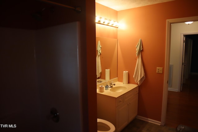 bathroom with vanity, hardwood / wood-style floors, a textured ceiling, and toilet