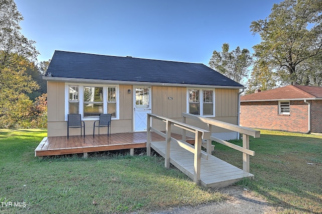 back of property with a wooden deck and a yard