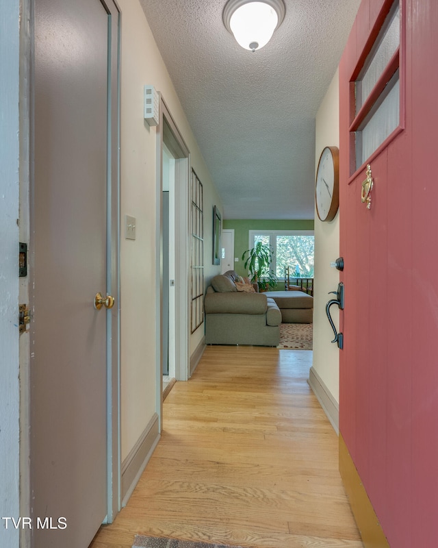 corridor featuring a textured ceiling and light hardwood / wood-style flooring