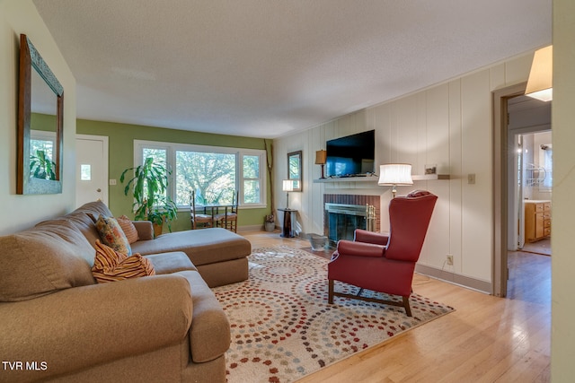 living room with a textured ceiling, light wood-type flooring, and a fireplace