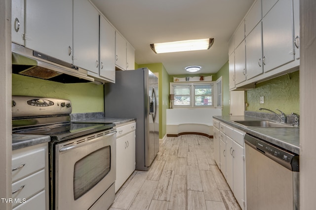 kitchen with appliances with stainless steel finishes, white cabinetry, sink, and light wood-type flooring