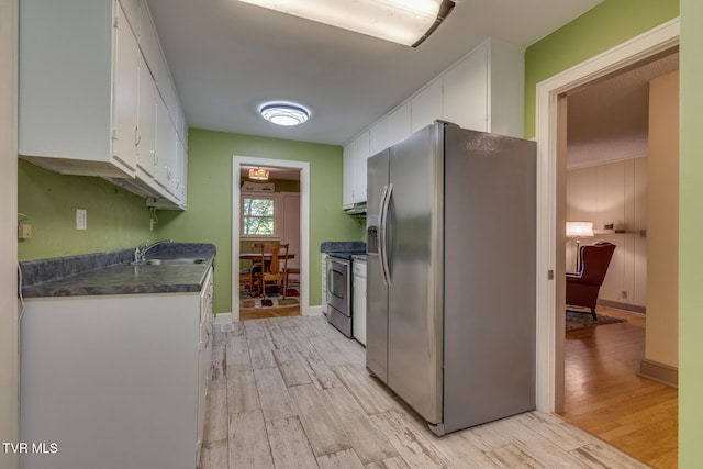 kitchen featuring appliances with stainless steel finishes, light hardwood / wood-style flooring, white cabinetry, and sink