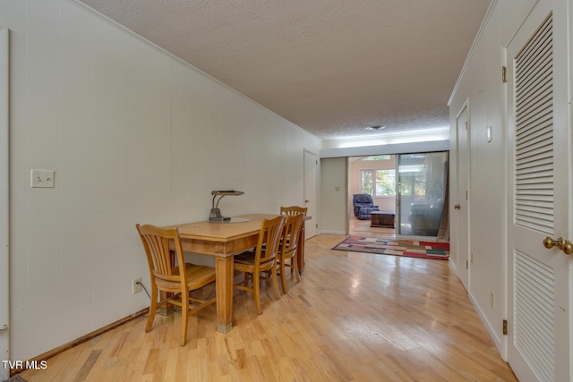 dining space with light hardwood / wood-style flooring, a textured ceiling, and crown molding