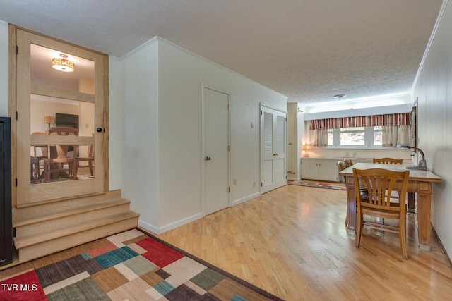 dining area featuring crown molding, a textured ceiling, and light hardwood / wood-style flooring