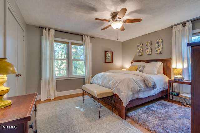 bedroom featuring ceiling fan, a textured ceiling, and light hardwood / wood-style floors
