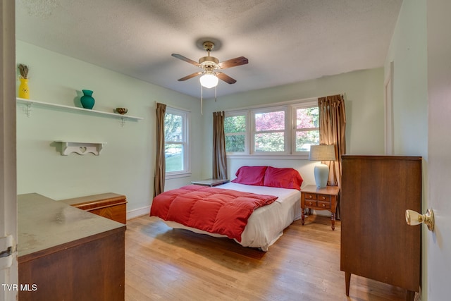 bedroom featuring ceiling fan, a textured ceiling, and light hardwood / wood-style flooring