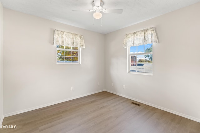 unfurnished room with wood-type flooring, plenty of natural light, a textured ceiling, and ceiling fan