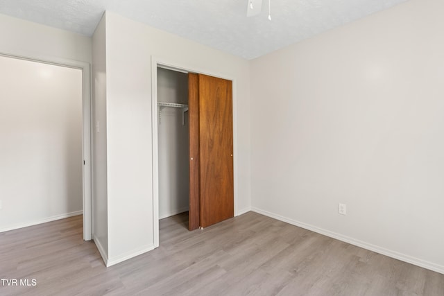 unfurnished bedroom with a closet, a textured ceiling, and light wood-type flooring