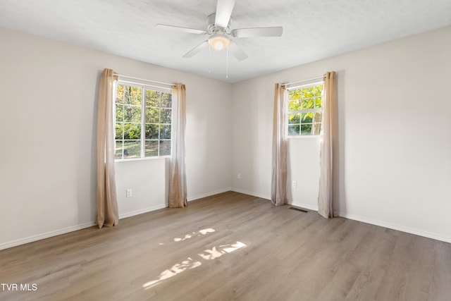 empty room featuring ceiling fan, light hardwood / wood-style floors, and a textured ceiling