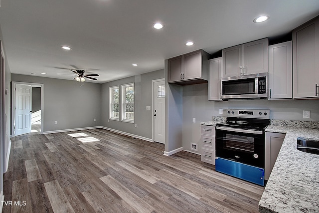 kitchen featuring gray cabinetry, ceiling fan, light stone countertops, light wood-type flooring, and stainless steel appliances