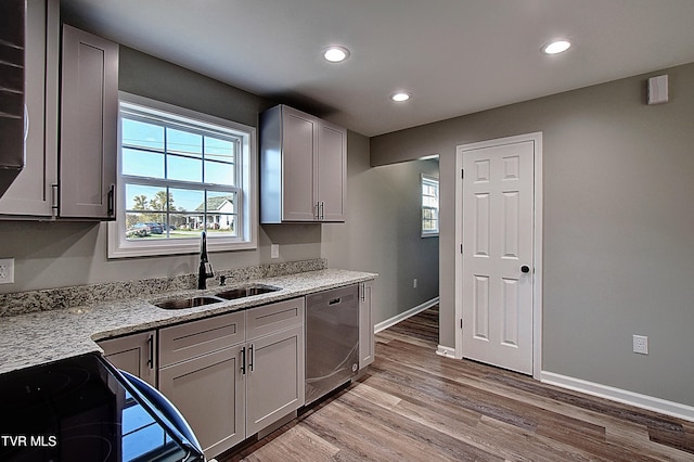 kitchen featuring dishwasher, light stone countertops, sink, and light hardwood / wood-style flooring