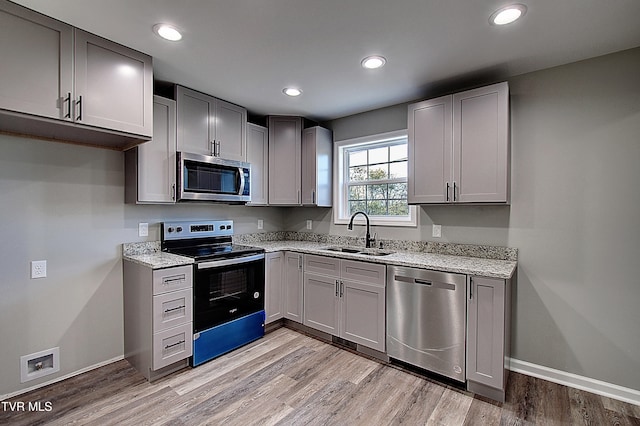 kitchen featuring gray cabinetry, sink, appliances with stainless steel finishes, and light hardwood / wood-style flooring