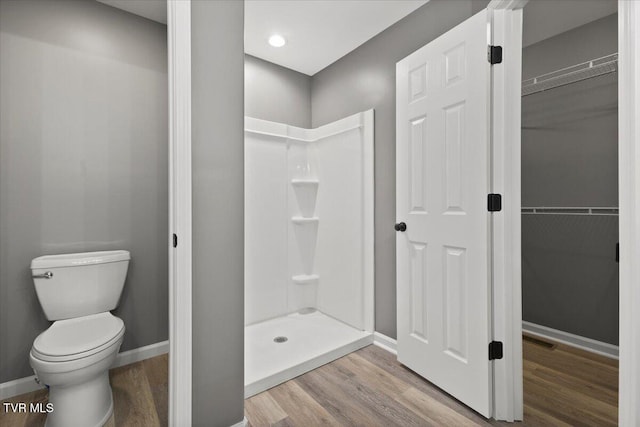 bathroom featuring a shower, hardwood / wood-style floors, and toilet