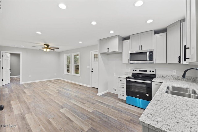 kitchen with ceiling fan, sink, light wood-type flooring, and stainless steel appliances