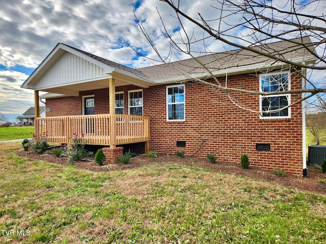 rear view of house featuring central AC, a yard, and covered porch