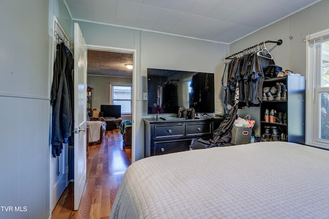 bedroom with crown molding, wooden walls, and dark hardwood / wood-style flooring