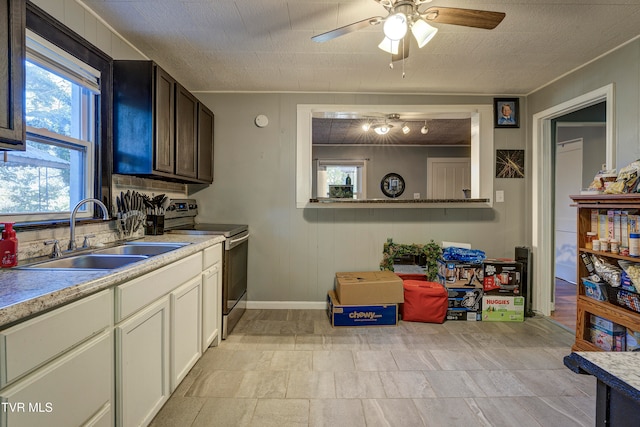 kitchen with dark brown cabinets, sink, stainless steel range with electric cooktop, white cabinets, and ceiling fan