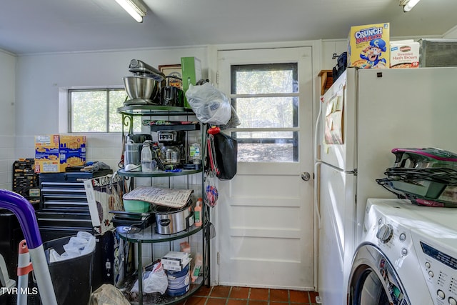 washroom featuring washer / clothes dryer, a healthy amount of sunlight, and dark tile patterned floors