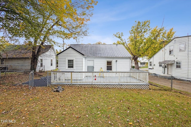 rear view of property with a wooden deck and a lawn