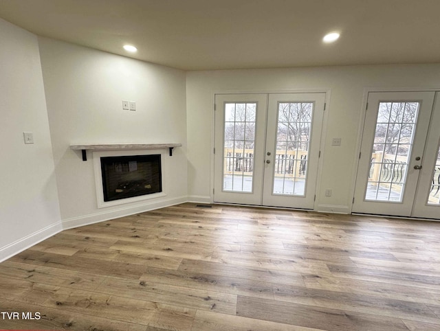 unfurnished living room featuring french doors and light hardwood / wood-style flooring