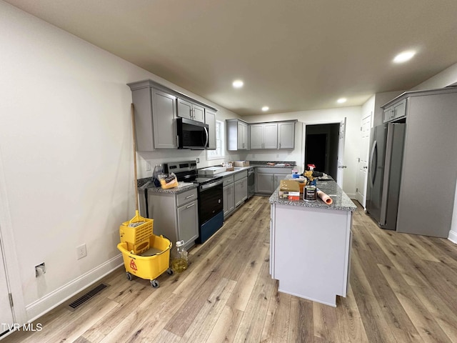 kitchen with stainless steel appliances, a kitchen island, gray cabinetry, and light hardwood / wood-style flooring