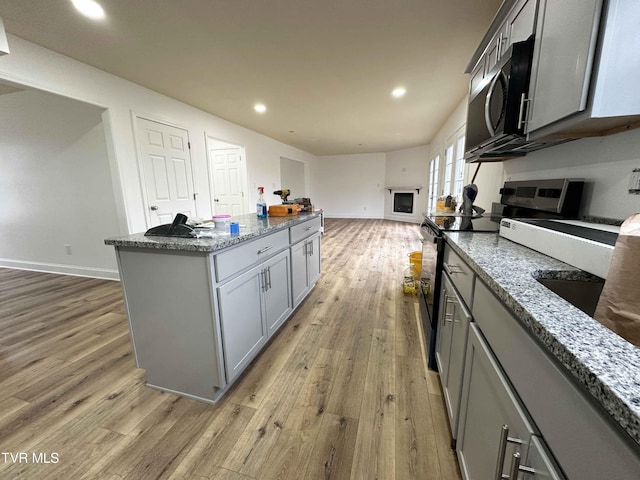 kitchen with a kitchen island, gray cabinets, light hardwood / wood-style flooring, and appliances with stainless steel finishes