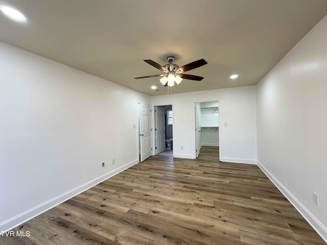 unfurnished bedroom with ceiling fan, dark hardwood / wood-style floors, and a spacious closet