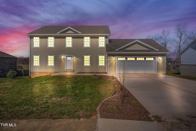 colonial-style house with a yard, an attached garage, driveway, and a shingled roof