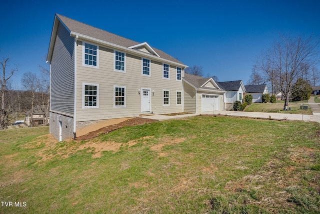 colonial-style house featuring an attached garage, concrete driveway, and a front yard