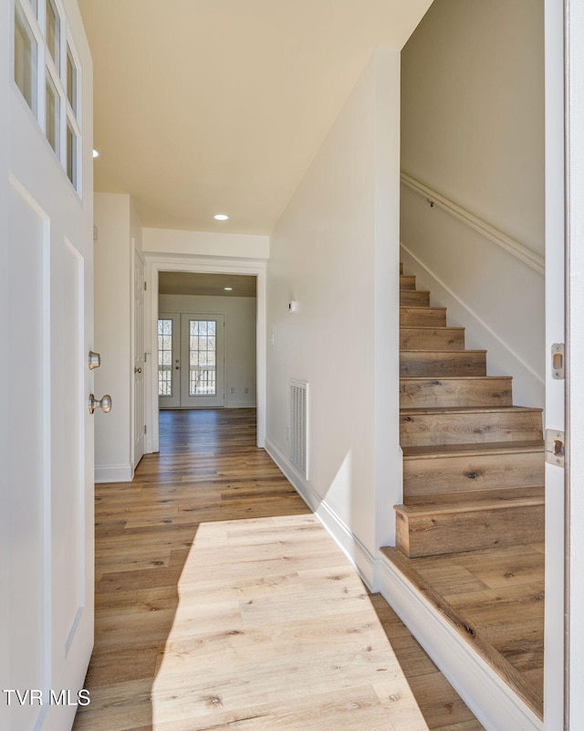 corridor with visible vents, baseboards, stairway, recessed lighting, and wood finished floors