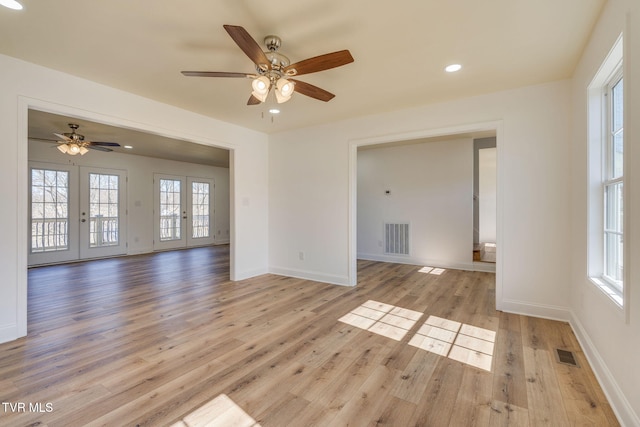 spare room featuring visible vents, light wood finished floors, plenty of natural light, and french doors