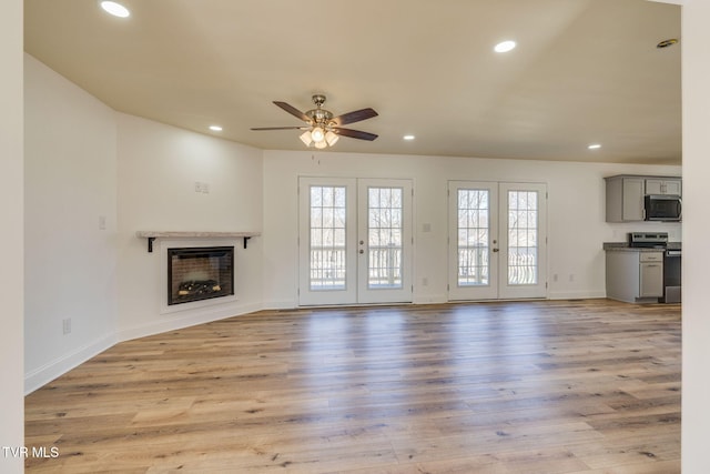 unfurnished living room with a fireplace, recessed lighting, french doors, and light wood finished floors