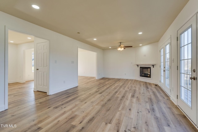 unfurnished living room featuring light wood finished floors, recessed lighting, a fireplace, and baseboards