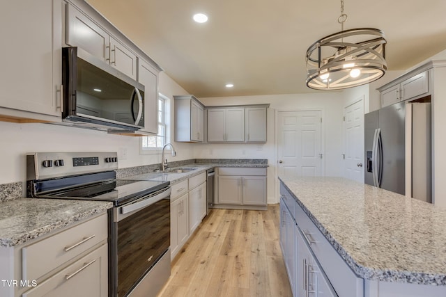 kitchen featuring gray cabinets, a sink, recessed lighting, stainless steel appliances, and light wood finished floors