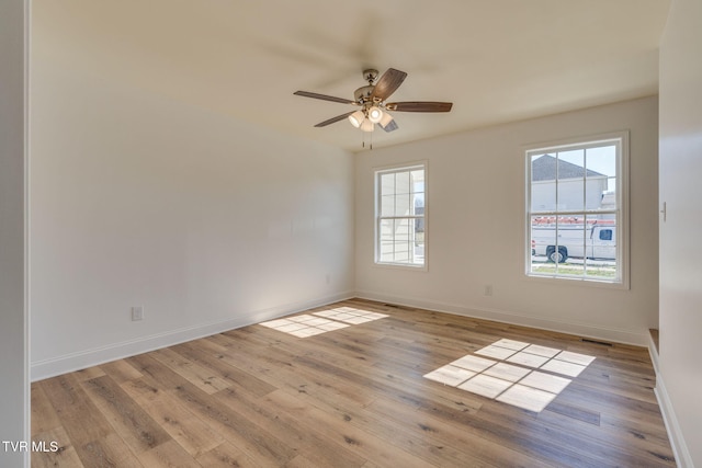 unfurnished room with visible vents, baseboards, wood finished floors, and a ceiling fan